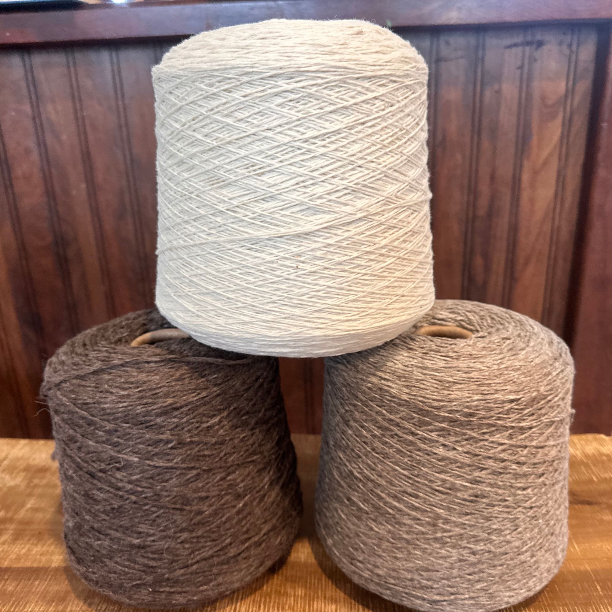 Undyed super fine Merino wool yarn in grey, white, and brown skeins and cones