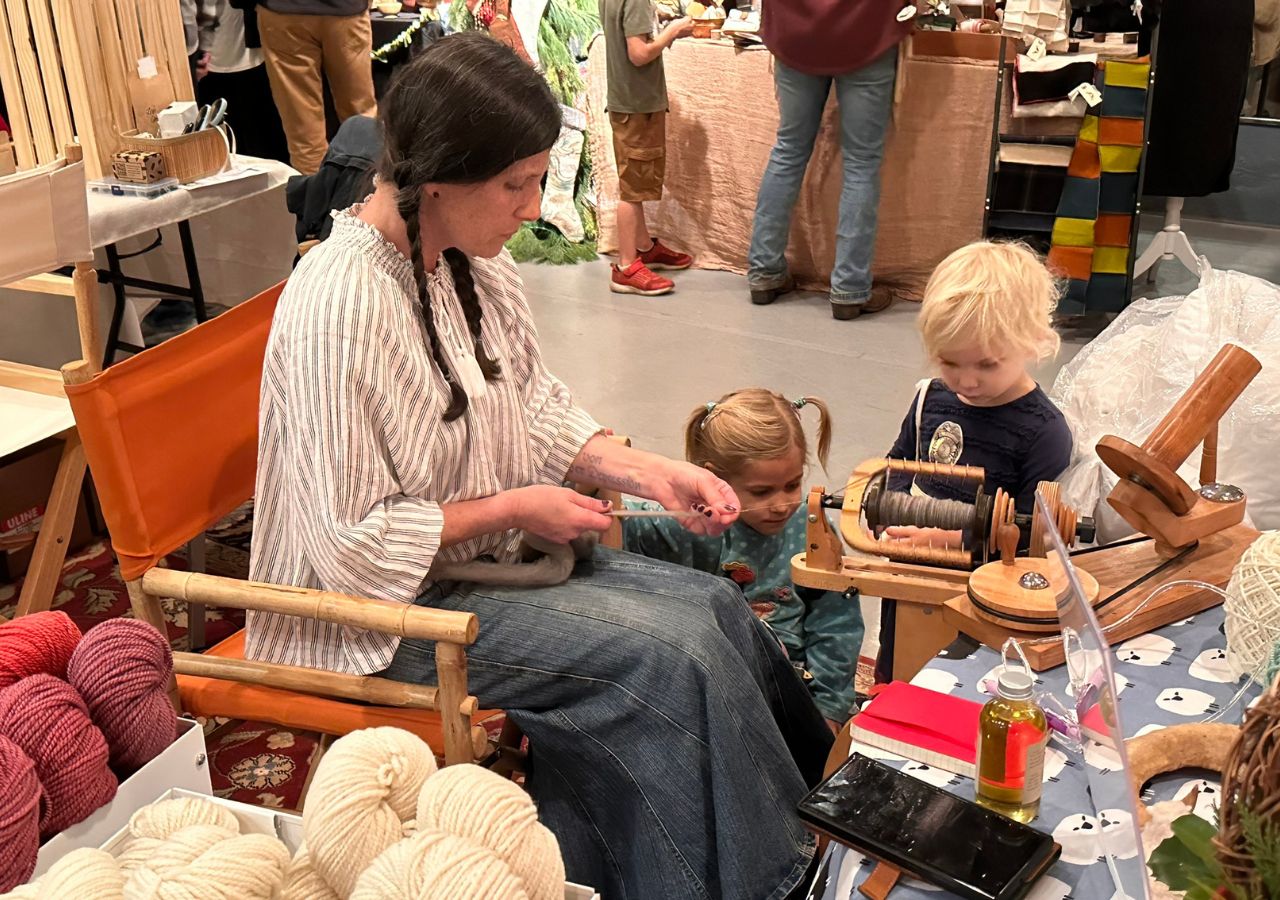 Michelle showing youngsters the craft of weaving with merino wool